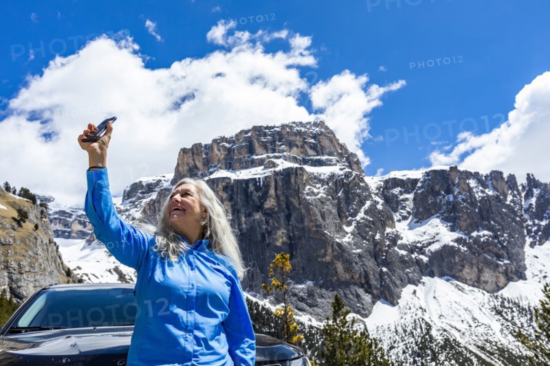 Woman taking photograph with smart phone by mountain in Dolomites, Italy