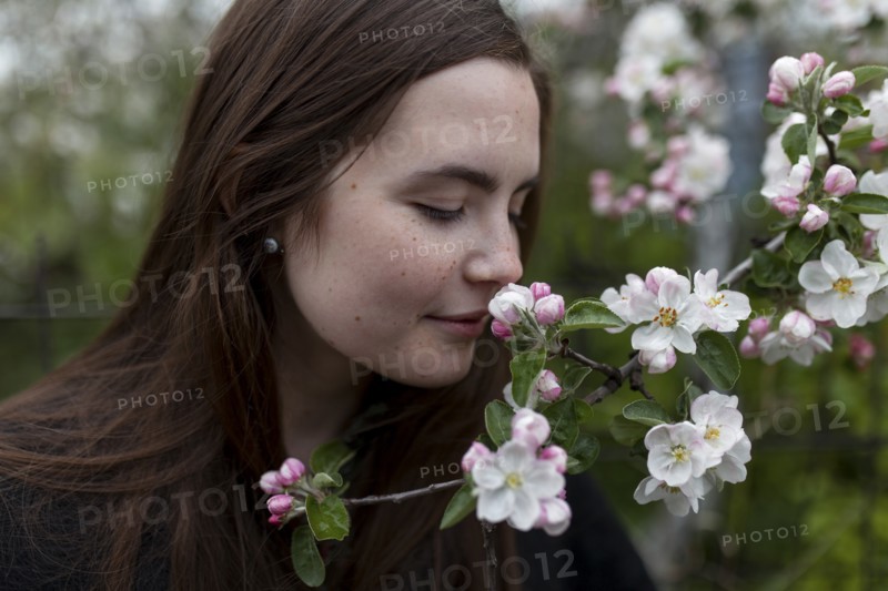 Young woman smelling white blossoms