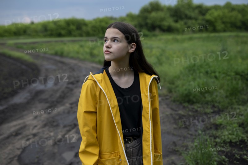 Teenage girl wearing yellow raincoat on country road