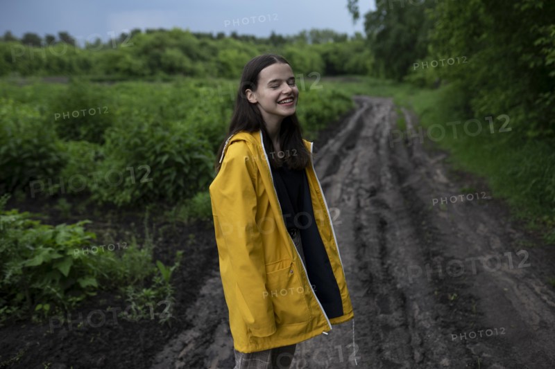 Smiling teenage girl wearing yellow raincoat on country road