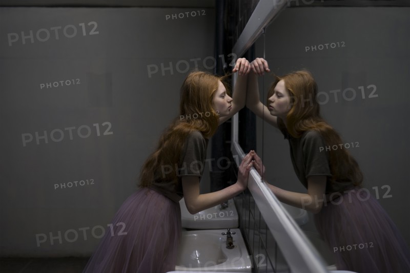 Young woman leaning on bathroom mirror
