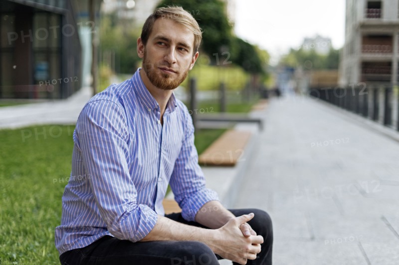 Man wearing striped shirt sitting on bench