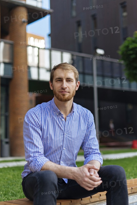 Man wearing striped shirt sitting on bench