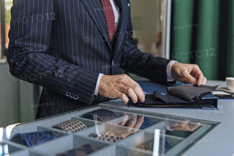 Shop assistant wearing pinstripe suit holding swatches
