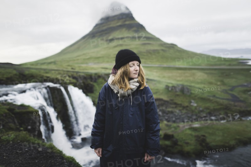 Young woman by Kirkjufell and Kirkjufellsfoss in Iceland
