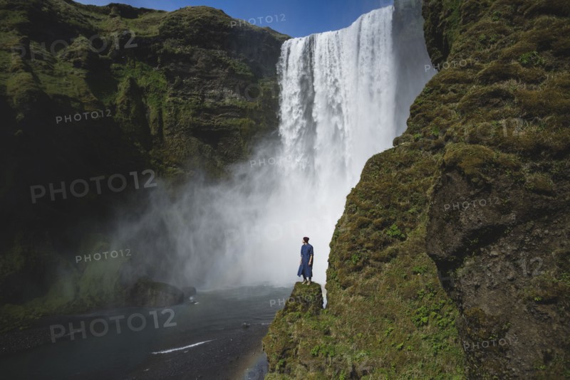 Man standing by Skogafoss waterfall in Iceland