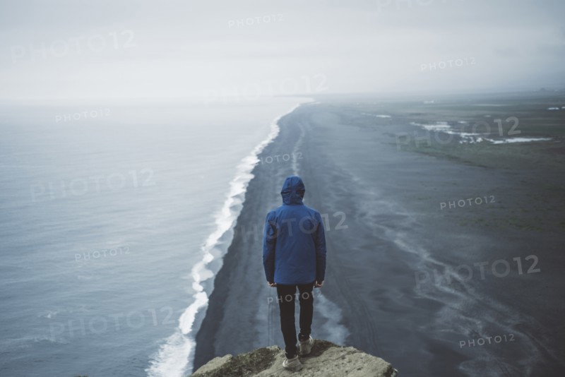 Man wearing blue coat above beach in Vik, Iceland