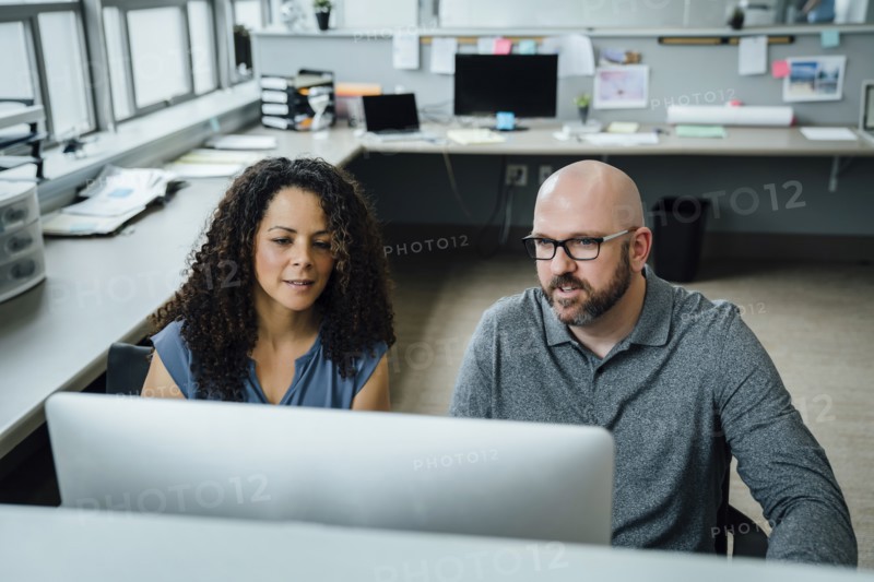 Coworkers using computer in office