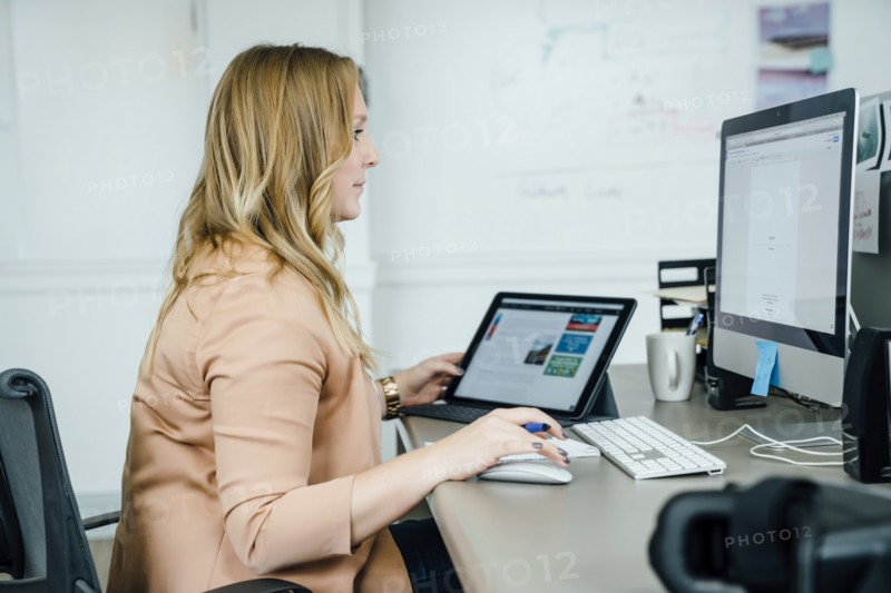 Woman using digital tablet and computer in office