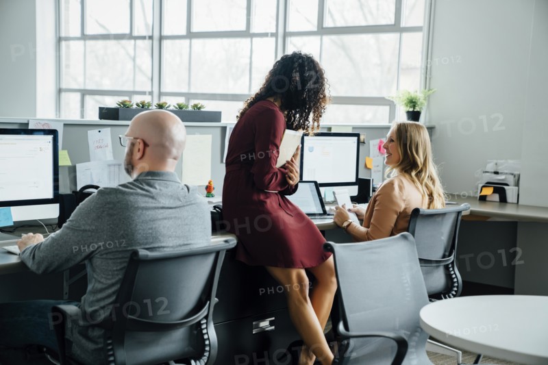 Coworkers talking at desk in office