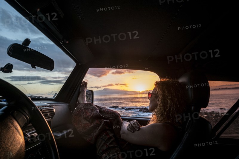 Woman in car with her legs raised watching sunset