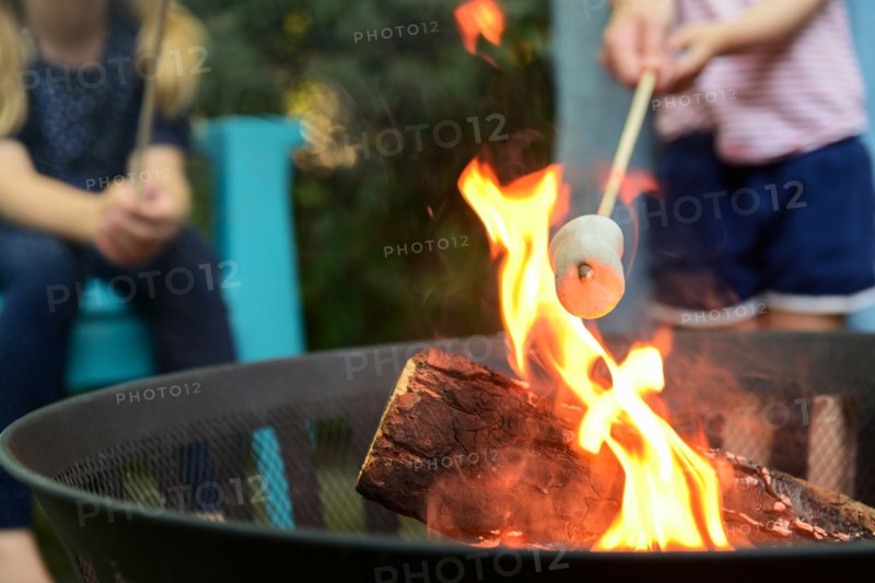 Family toasting marshmallows over brazier