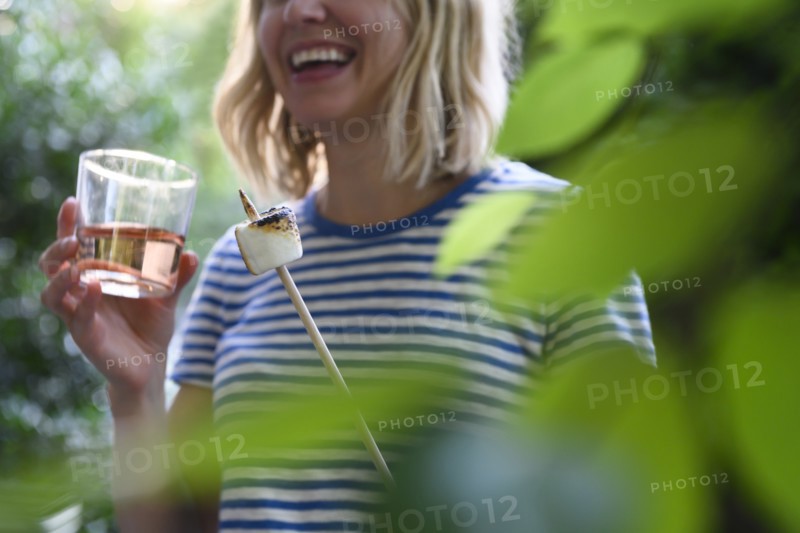 Smiling woman holding glass of wine and toasted marshmallow