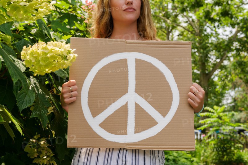 Woman holding peace symbol by trees