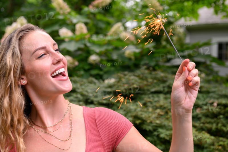 Smiling young woman holding sparkler