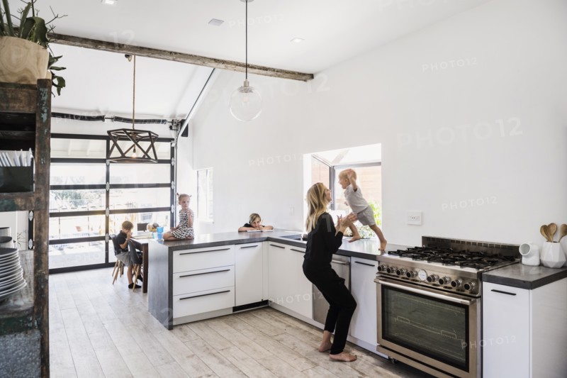Mother catching son jumping off kitchen counter