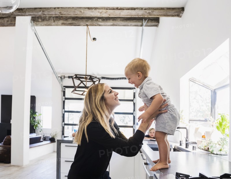 Mother holding son on kitchen counter