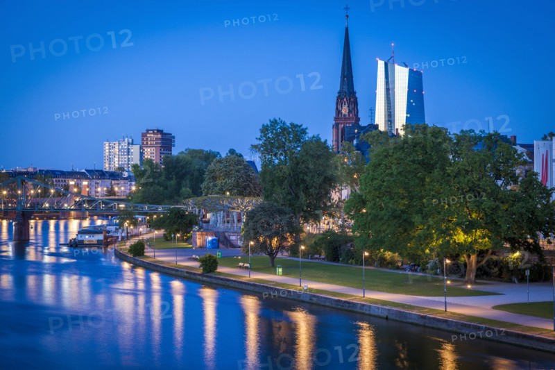 Church and office towers by river at sunset in Frankfurt