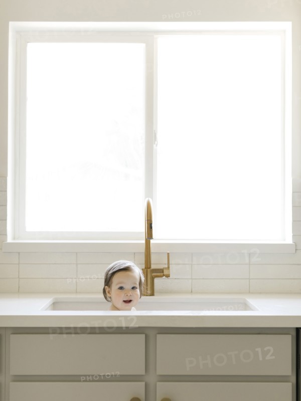 Baby girl bathing in kitchen sink