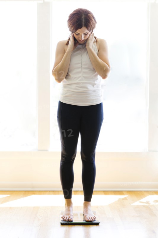 Mid adult woman weighing herself