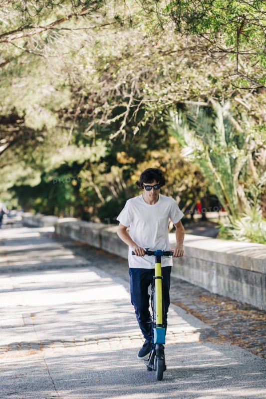 Young man using electric scooter on pavement