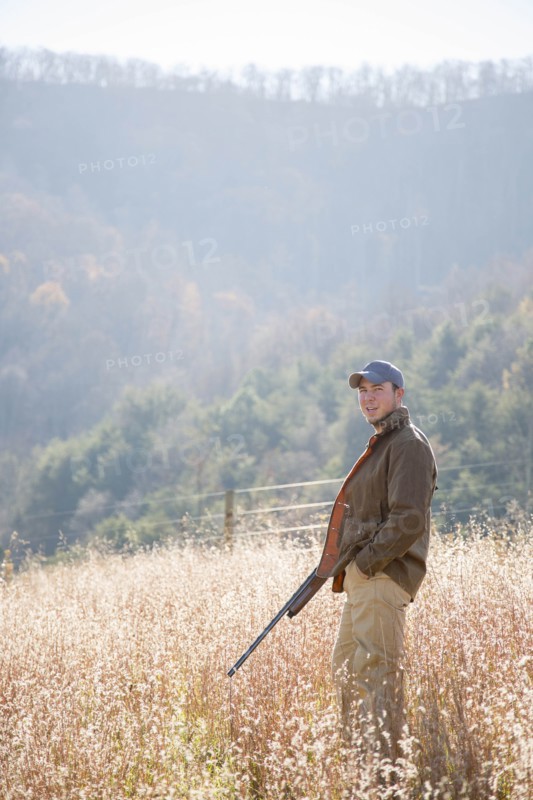 Young man holding rifle in field