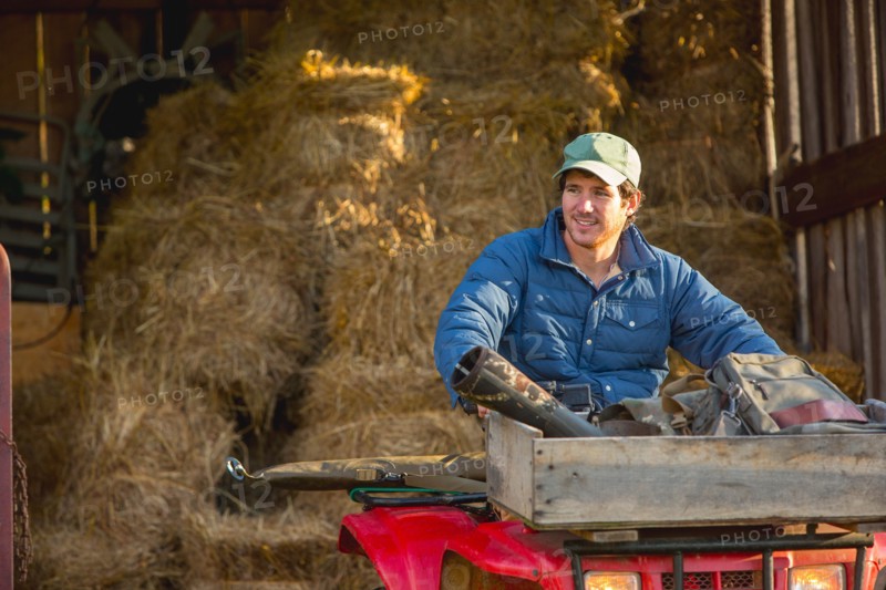 Young man driving 4x4 out of barn