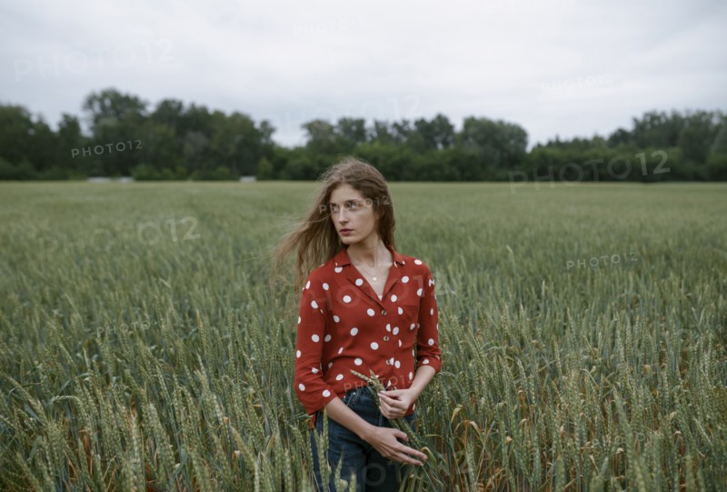 Woman wearing red polka dot shirt in wheat field