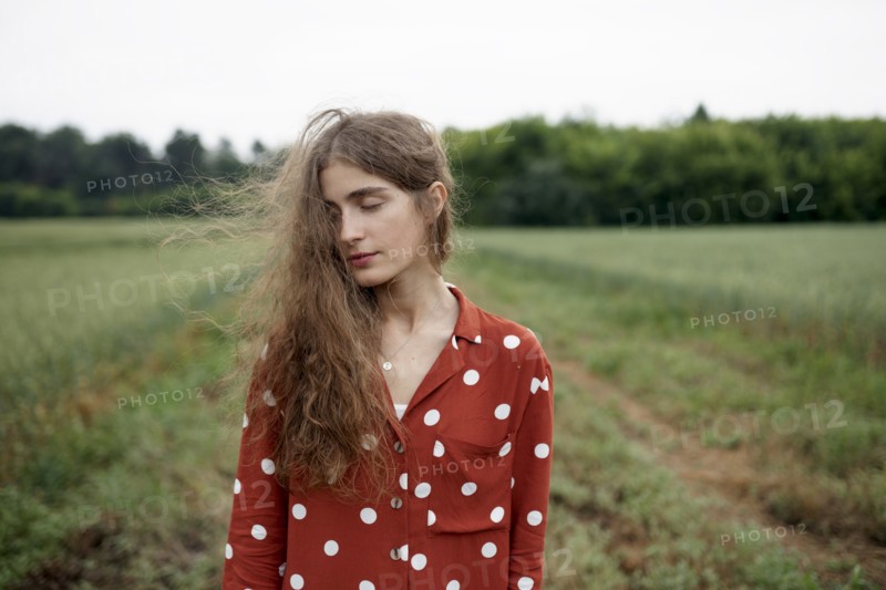 Woman wearing red polka dot shirt in wheat field