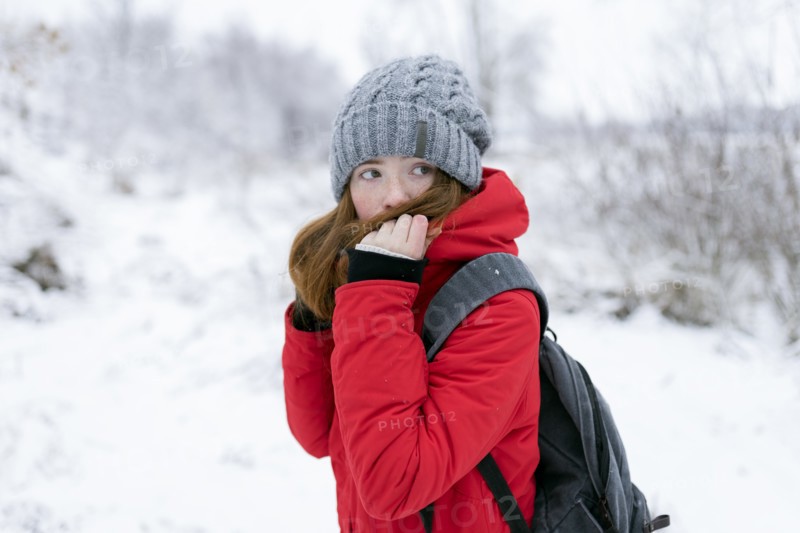 Teenage girl wearing red coat and grey hat in snow