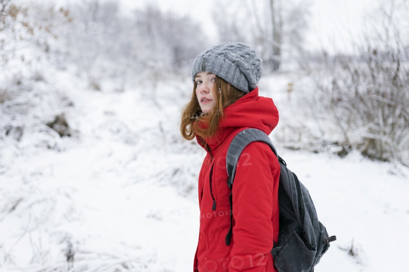 Teenage girl wearing red coat and grey hat in snow