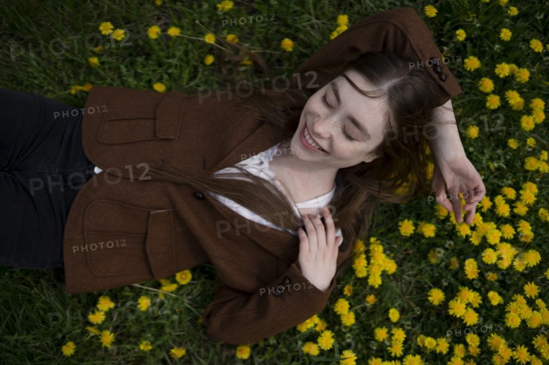 Smiling young woman lying on yellow flowers