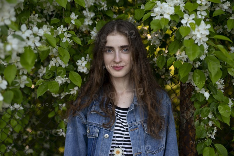 Young woman wearing denim jacket by white flowers