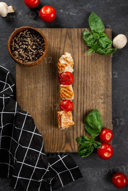 Grilled chicken and tomato skewer on cutting board