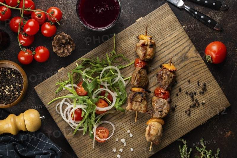 Grilled meat skewers and salad on cutting board
