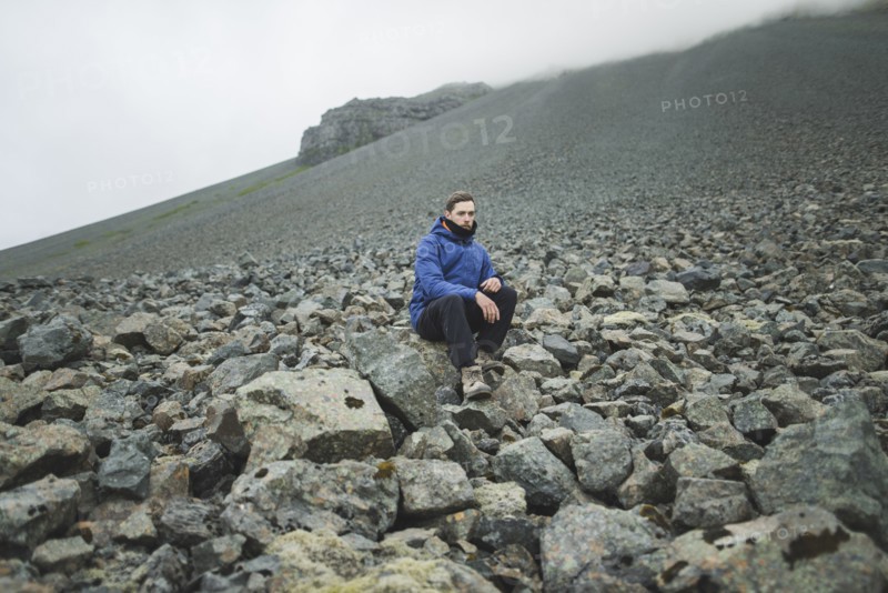 Young man sitting on rock hill in Kirkjubµjarklaustur