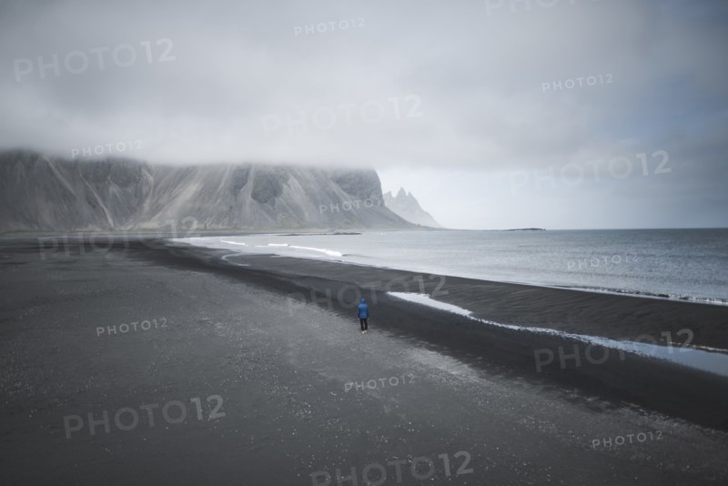Man walking on black sand beach in Kirkjubµjarklaustur