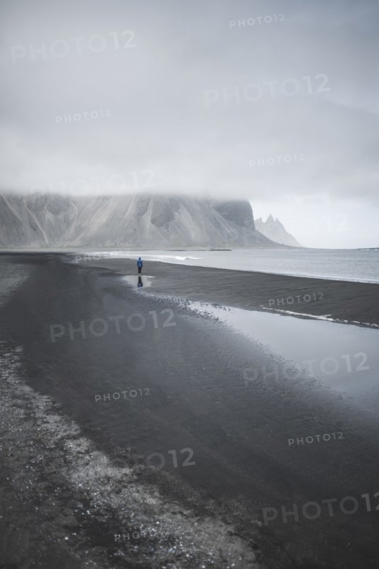 Man walking on black sand beach in Kirkjubµjarklaustur