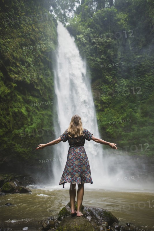 Woman standing by waterfall in Bali