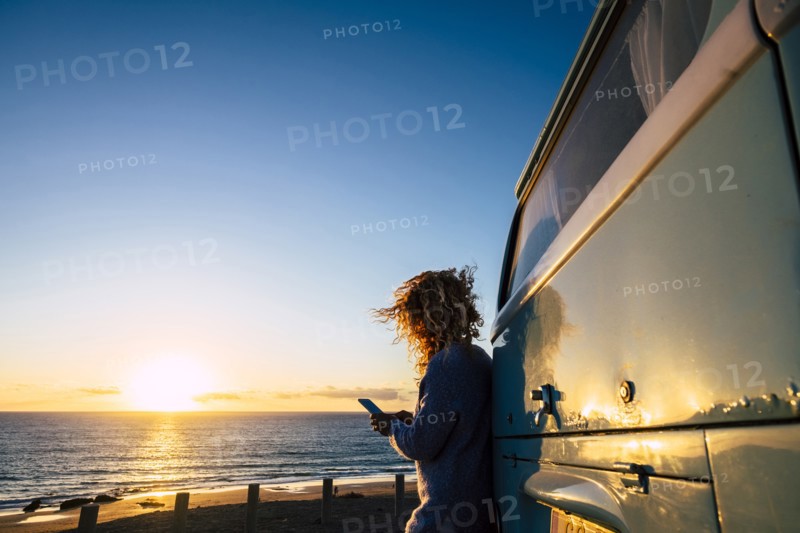 Woman using smart phone by beach at sunset in Fuerteventura