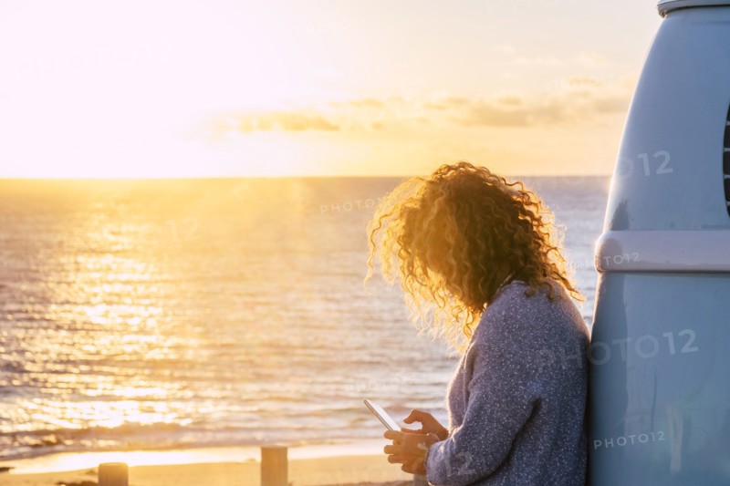 Woman using smart phone by beach at sunset in Fuerteventura