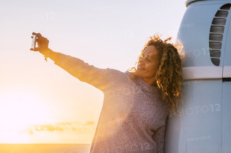 Woman taking selfie by camper van at sunset