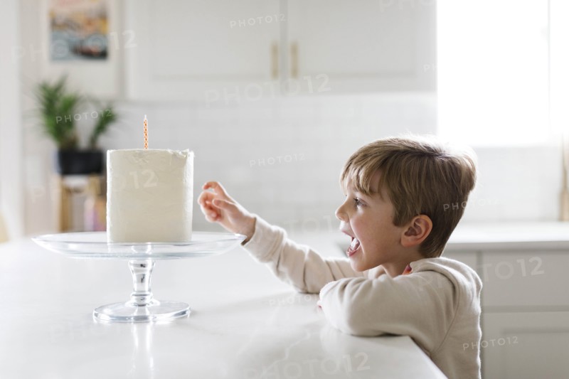 Boy reaching for birthday cake