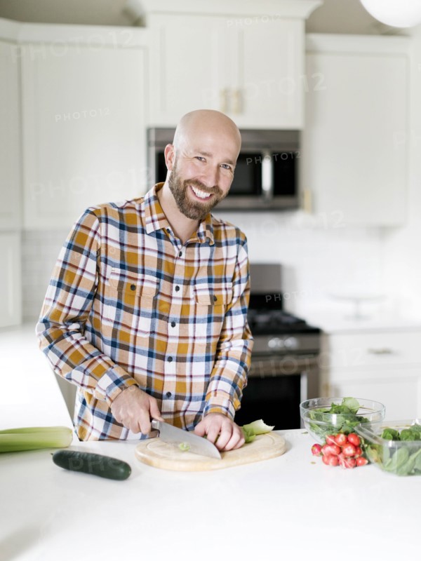 Smiling man chopping vegetables in kitchen