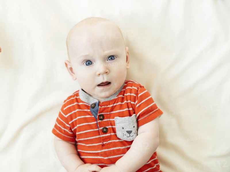 Confused baby boy lying on bed