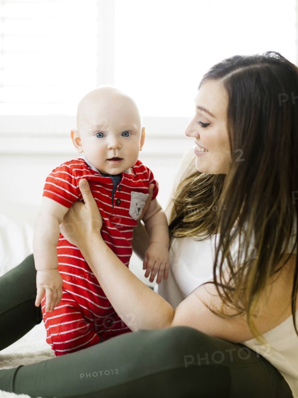 Smiling woman holding her son on bed
