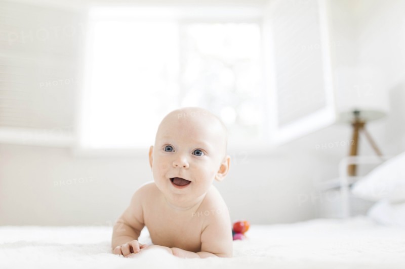 Shirtless baby boy lying on bed