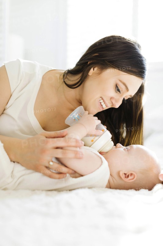Mother watching her baby boy drink milk from bottle