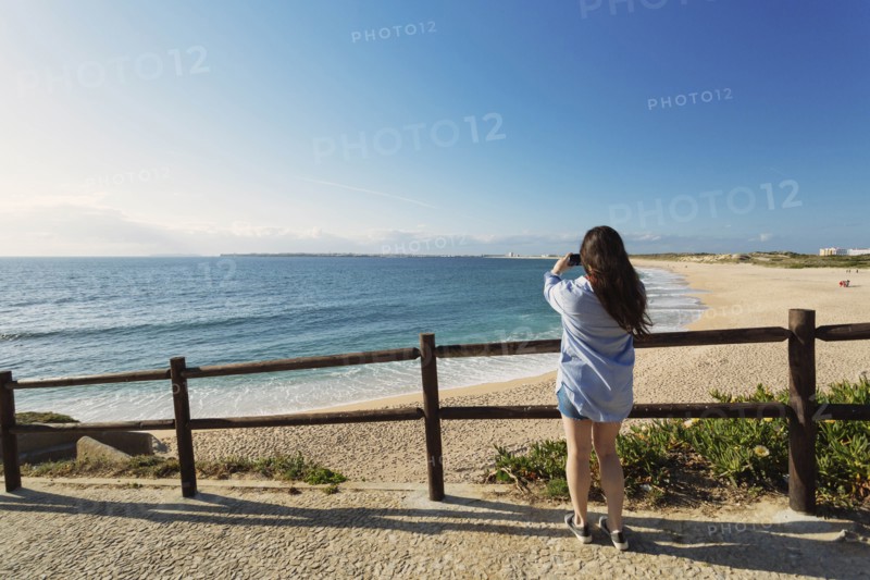Woman photographing beach in Lisbon, Portugal