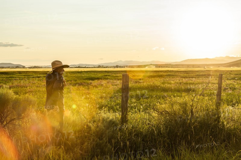 Farmer by fence at sunset in Picabo, Idaho, USA